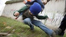 Schulkind wird von älterem Kind auf den Boden geworfen. | Bild: picture-alliance/dpa