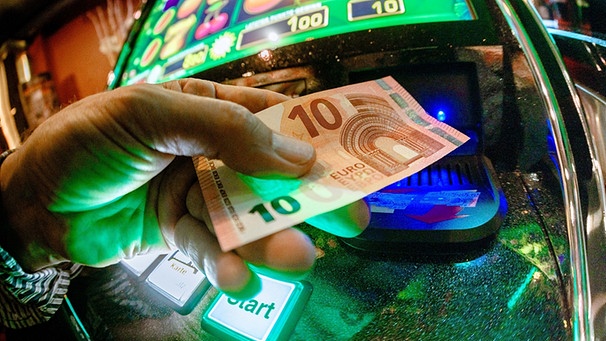 Junger Mann schiebt Zehn-Euro-Schein in Glücksspielautomat | Bild: picture-alliance/dpa
