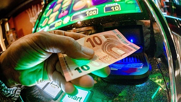 Junger Mann schiebt Zehn-Euro-Schein in Glücksspielautomat | Bild: picture-alliance/dpa