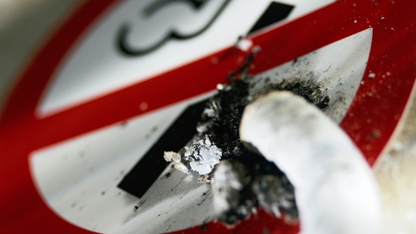 Ein Riskofaktor für einen Schlaganfall ist das Rauchen - im Bild: ausgedrückte Zigarettee auf einem Rauchverbotsschild | Bild: Getty Images