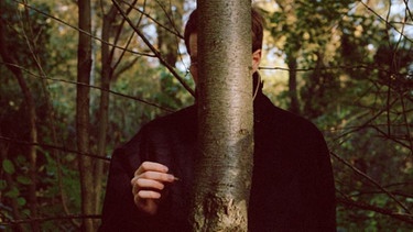 Jakob Nolte hinter einem Baum | Bild: Rachel Israela