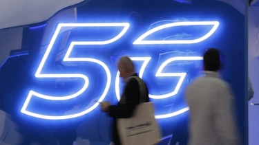 Besucher gehen beim Mobile World Congress 2019 an einer 5G-Anzeige vorbei | Bild: picture-alliance/dpa