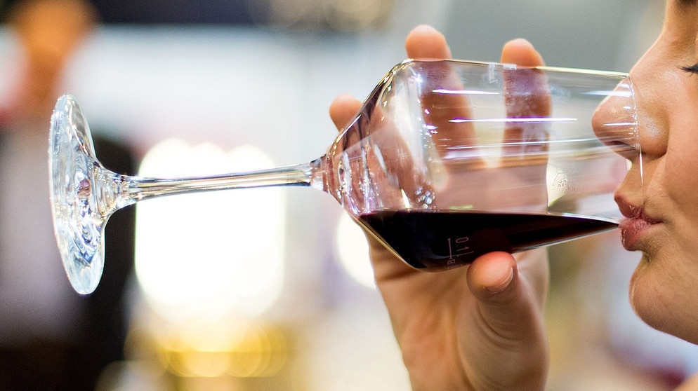 Eine Frau trinkt Rotwein aus einem Glas | Bild: picture-alliance/dpa