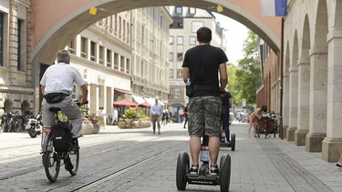 Mann fährt auf Segway Elektroroller durch eine Altstadt | Bild: picture-alliance/dpa