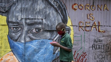 Ein Junge mit Gesichtsschutz vor einem Graffiti in Nairobi | Bild: picture-alliance/dpa