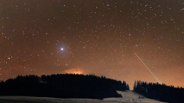 Eine Sternschnuppe verglüht am Nachthimmel über dem Auerberg in Bayern | Bild: BR