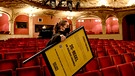 Eine Frau trägt ein Schild mit dem Hinweis auf die 2G-Regel durch den Zuschauerraum des Berliner Ensembles | Bild: picture-alliance/dpa