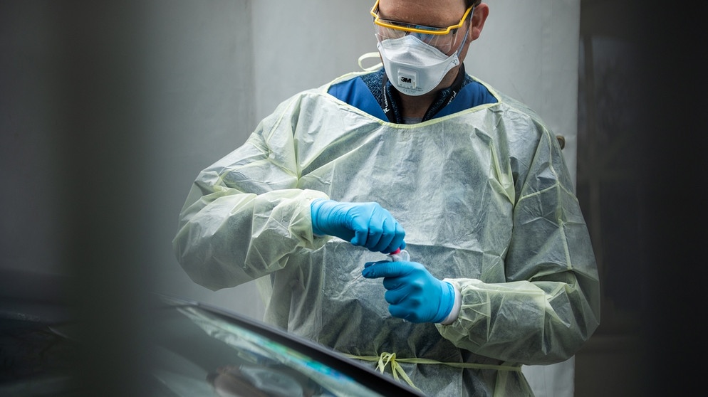 Eine Mitarbeiter der Corona-Teststelle am Tropeninstitut München nimmt einen Abstrich | Bild: BR