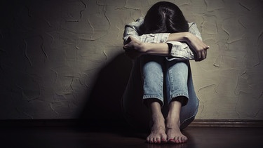 Frau sitzt alleine auf dem Boden, den Kopf in die angezogenen Knie vergraben | Bild: colourbox.com