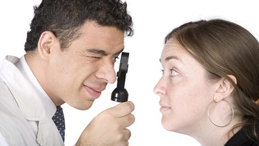 Arzt untersucht Frau mit einer Lupe | Bild: picture-alliance/dpa