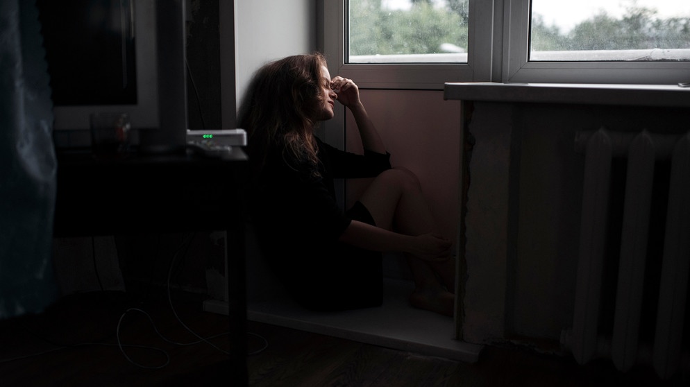 Themenbild: Häusliche Gewalt, eine junge Frau sitzt am Fenster | Bild: picture-alliance/dpa