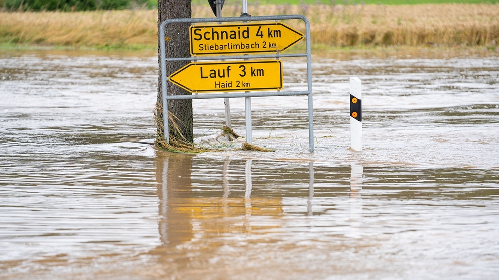 Die über die Ufer getretene Aisch hat eine Landstraße überschwemmt. Aufnahmedatum: 11.07.2021 | Bild: picture-alliance/dpa
