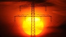 Ein Strommasten vor einer untergehenden Sonne. | Bild: picture alliance/ dpa/ Julian Stratenschulte