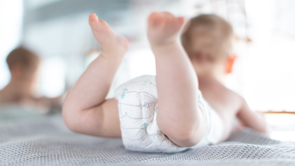 Ein Säugling trägt Windeln, während er auf einer Kommode liegt. | Bild: picture-alliance/dpa