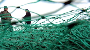 Fischer bereiten am 04.05.2010 im Fischereihafen von Lübeck-Travemünde ihre Fangnetze für die nächste Fahrt vor. Die Weltmeere sind nach Expertenanalysen weit stärker überfischt als offiziell angegeben.  | Bild: picture-alliance/dpa