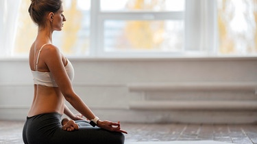 Eine Frau sitzt im Lutus-Sitz auf einer Yogamatte | Bild: colourbox.com
