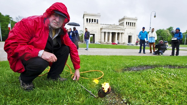 Wolfram Kastner brennt auf dem Königsplatz in München ein Loch in den Rasen. Er erinnert damit an die Bücherverbrennung durch die Nationalsozialisten im Jahr 1933 an diesem Platz. (2013) | Bild: picture alliance/dpa/Inga Kjer