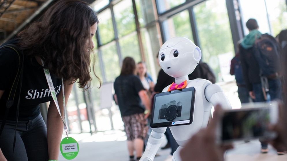 Ein Roboter kommuniziert auf einer Messe mit Menschen | Bild: dpa-Bildfunk