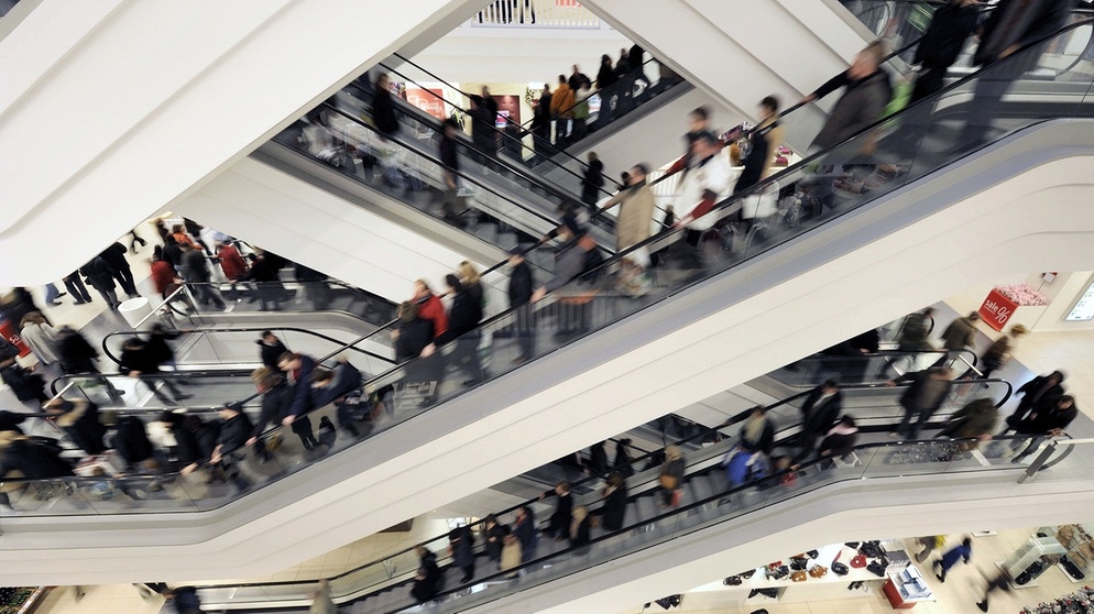 Menschen im kaufhaus: Permanenter Konsum will finanziert sein, und wer dauernd konsumiert, hat für nichts anderes mehr Zeit. | Bild: picture-alliance/dpa