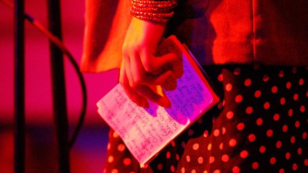 Symbolbild: Junge Frau mit handgeschriebenem Text in der Hand neben einem Mikrofon | Bild: picture-alliance/dpa