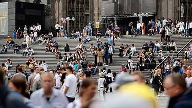 Menschen sitzen auf der Domtreppe in Köln | Bild: picture alliance / Panama Pictures | Christoph Hardt