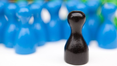 Symboldbild schwarze Spielfigur unter blauen Spielfiguren | Bild: picture-alliance/dpa