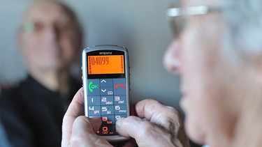 Eine ältere Frau benutzt ein spezielles Senioren-Mobiltelefon. | Bild: picture-alliance/dpa