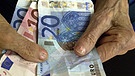 Eine alte Dame sitzt in einem Seniorenheim und hat Geldscheine in den Händen | Bild: picture-alliance/dpa