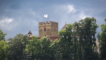 Turm des Schlosses Neubeuern hinter grünem Laub. | Bild: Colourbox