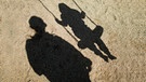 Schatten eines Mannes und eines Kindes auf der Schaukel | Bild: picture alliance / dpa | Julian Stratenschulte