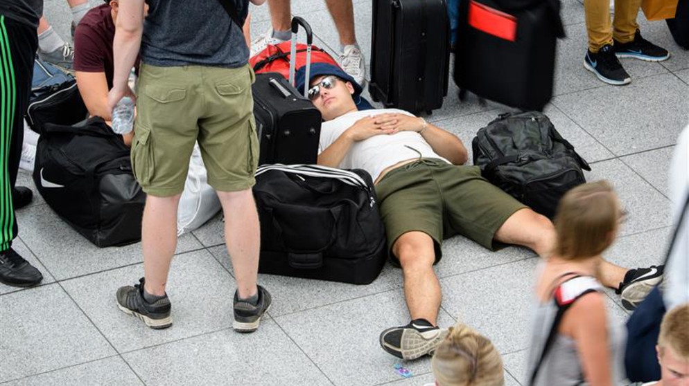 Mann liegt auf Flughafen am Boden und schläft auf seinem Gepäck | Bild: picture alliance/dpa | Matthias Balk
