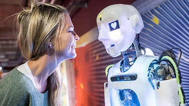 Fühlst Du mich, Bot? Wie einfühlsam kann Künstliche Intelligenz sein (Frau und Roboter lächeln sich an)  - Symbolbild  | Bild: picture alliance_Westend61