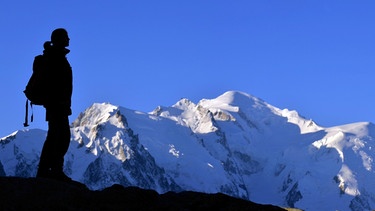 Bergsteigerin am Gipfel vor Gebirgspanorama | Bild: picture-alliance/dpa