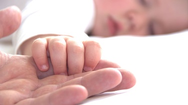 Baby greift im Schlaf nach der Hand des Vaters | Bild: colourbox.com