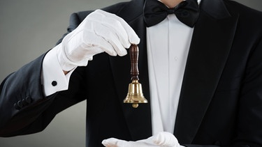 Butler mit Anzug, Fliege und einer Glocke in der Hand | Bild: picture-alliance/dpa