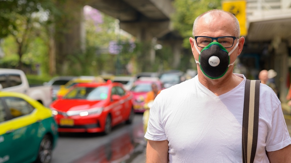Mann steht mit Gasmaske an einer vielbefahrenen Straße | Bild: picture-alliance/dpa