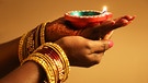 Eine Anhängerin des Hinduismus hält eine Diya (kleine Tonlampe) in der Hand und hört zu, wie während des Diwali-Festes in einem Hindu-Tempel in Toronto, Ontario, Kanada, am 4. November 2021 Gebete gesprochen werden. | Bild: picture alliance / NurPhoto | Creative Touch Imaging Ltd