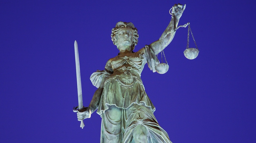 Die Statue der Göttin Justitia steht beleuchtet und mit der Waage und dem Richtschwert auf dem Justitia-Brunnen vor dem Römer in Frankfurt/Main. | Bild: picture-alliance/dpa