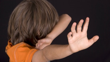 Ein Junge wehrt sich und hält sich die Arme schützend vor das Gesicht | Bild: picture-alliance/dpa