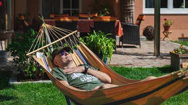 Ein Mann genießt die Sonne in seinem Urlaub in der Hängematte im Garten. | Bild: BR/Sylvia Bentele