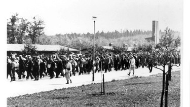 Ankunft eines Häftlingstransportes. Die Häftlinge marschieren auf dem Carachoweg in Richtung Lagertor. Das Bild wurde vom Kommandanturgebäude aus fotografiert. Links im Hintergrund die Politische Abteilung | Bild: Sammlung Gedenkstätte Buchenwald