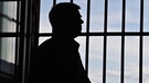 Silhouette von Mann vor Gitterstäben | Bild: picture-alliance/dpa