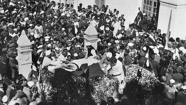 Eine riesige Menschenmenge umgibt die Leiche von Mahatma Gandhi der am 30. Januar 1948 erschossen wurde. | Bild: picture-alliance/dpa