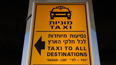 Englisch- und hebräischsprachiges Hinweisschild zu Shuttle-Möglichkeiten in andere Städte auf dem Flughafen in Tel Aviv. | Bild: picture alliance / zb | Matthias Tödt