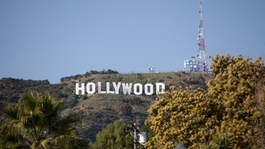 Strassenszene mit dem Hollywood-Sign im Hintergrund.  | Bild: picture alliance / Frank Duenzl 