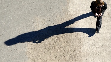 Frau läuft und wirft langen Schatten auf den Boden | Bild: picture-alliance/dpa