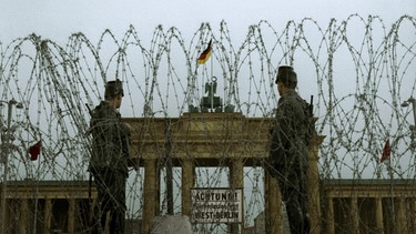 Stacheldraht vor dem Brandenburger Tor und zwei Soldaten davor | Bild: picture alliance / akg-images 