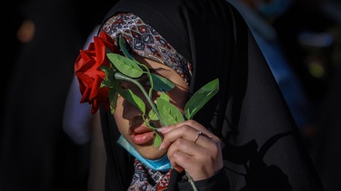 Eine muslimische Frau verdeckt ihr Gesicht mit einer künstlichen Rose | Bild: dpa-Bildfunk/ Ameer Al Mohammedaw
