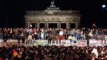 Feiernde Menschen auf der Berliner Mauer beim Mauerfall | Bild: BR