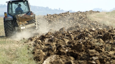 Traktor beim Pflügen eines Feldes | Bild: picture-alliance/dpa